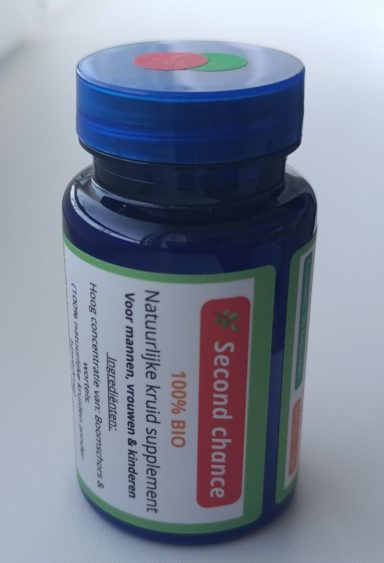 Nieuw flesje met blauwe dop, rood-groen etiket en inhoud van een rauw kruidensupplement, geschikt voor spoedbehandeling.